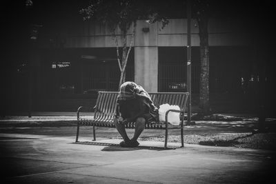 Full length of man sitting on chair at railroad station