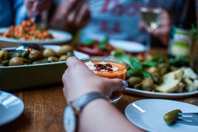 Cropped image of hand holding food in bowl on table