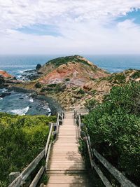 Footpath leading towards sea against sky