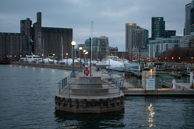 Boats in river against illuminated buildings in city