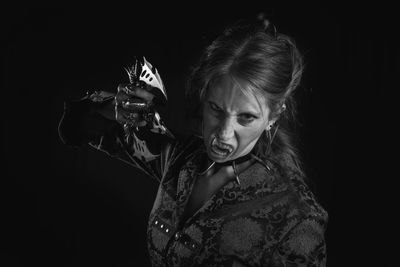 Portrait of spooky woman standing against black background