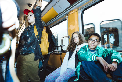 Multiracial male and female friends traveling by tram during weekend