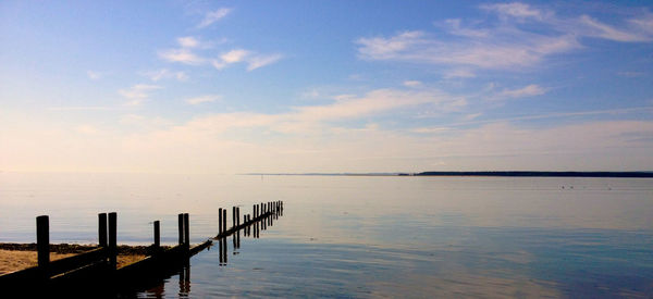 Pier in sea at sunset