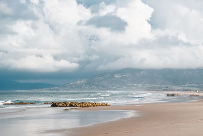 Scenic view of beach and mountains against sky