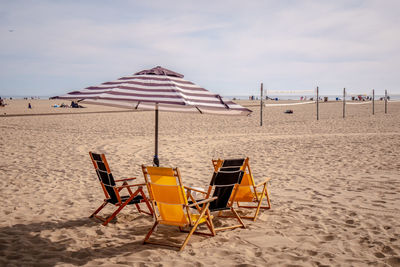 Deck chairs on beach against sky