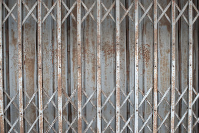 Full frame shot of rusty metal fence against wall