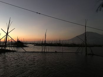 Silhouette sailboats in sea against sky during sunset