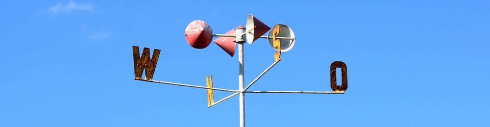 Low angle view of weather vane against clear blue sky