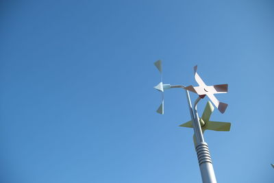 Low angle view of pinwheel against clear blue sky