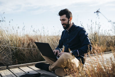 Young man using mobile phone while sitting on grass