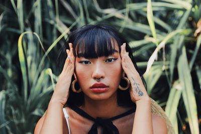 Portrait of young woman sitting against plants