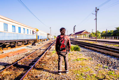 Rear view of man standing on railroad track