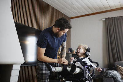 Father taking care of disabled child in wheelchair at home