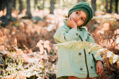 Cute girl looking away while standing in forest