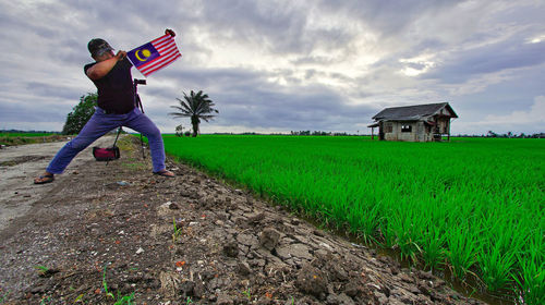Man holding malaysian flag while standing on field