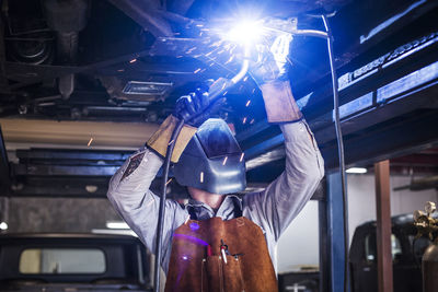 Mechanic welding car in auto repair shop