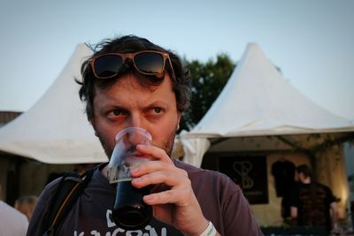 Close-up of man drinking craft beer against tent during sunset