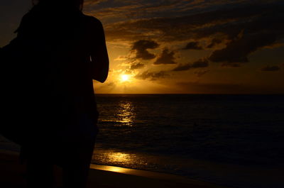 Silhouette woman standing at beach during sunset