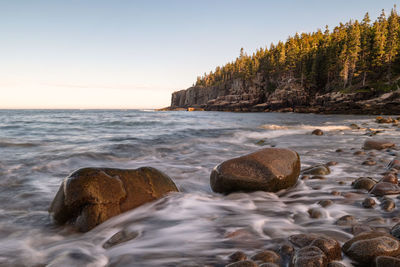 Scenic view of sea and rocks against clear sky