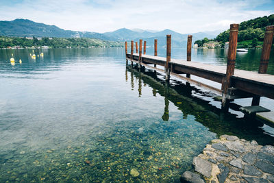 Wooden pier on orta san giulio lake with mountain scenery background. italy.