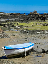 Deck chairs on shore against clear blue sky