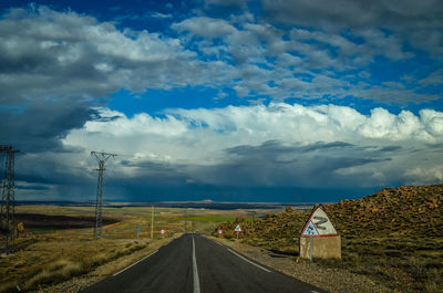 Road amidst field against sky