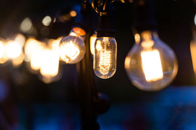 Close-up of illuminated light bulb hanging outdoors