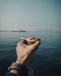 Midsection of person holding sea against sky