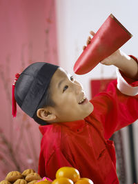 Close-up of teenage boy in traditional clothes looking through paper