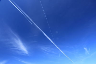 Low angle view of vapor trails in blue sky