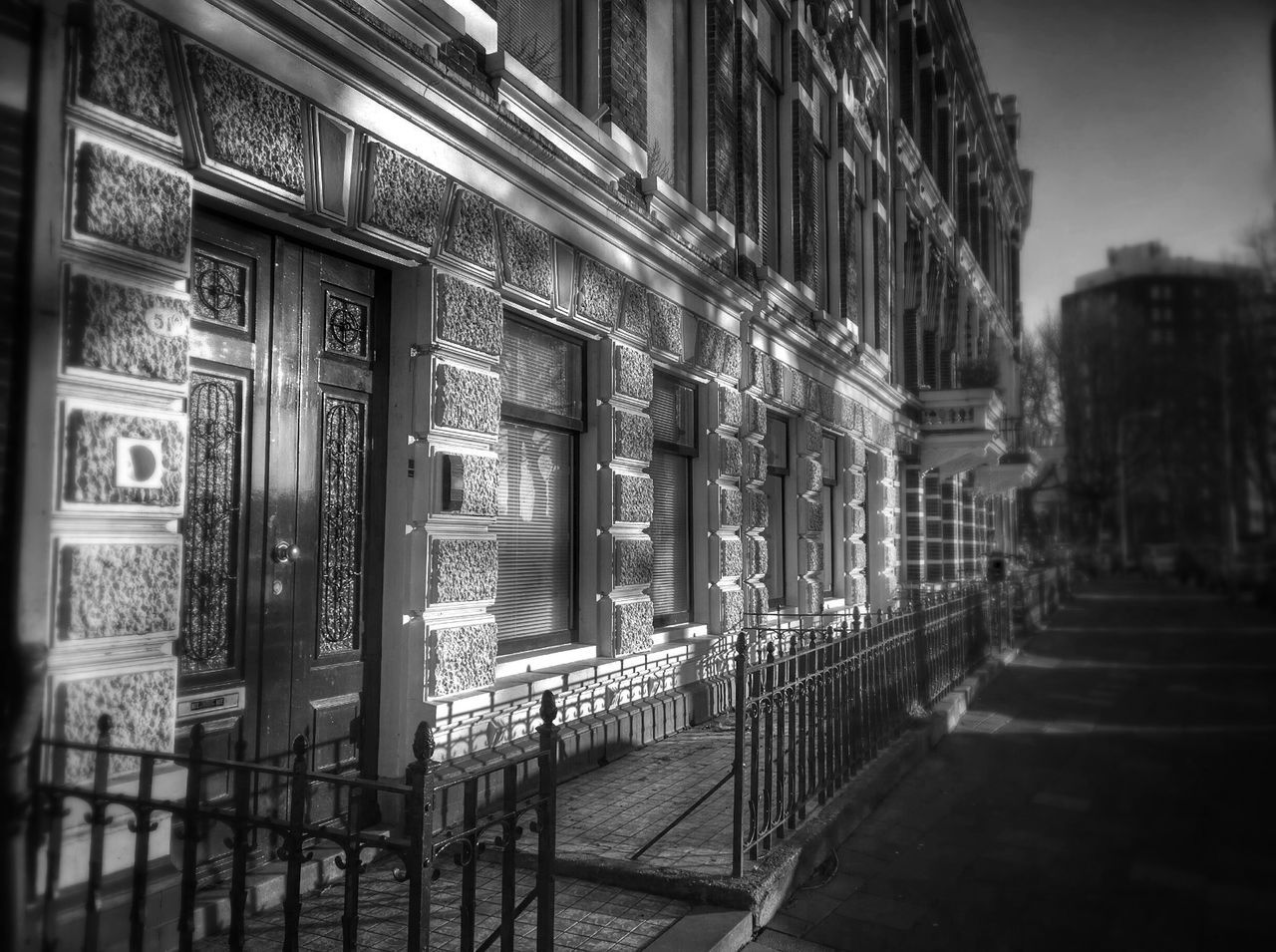 architecture, built structure, building exterior, building, city, in a row, street, railing, architectural column, window, no people, outdoors, day, incidental people, text, residential structure, residential building, road, sidewalk, sky