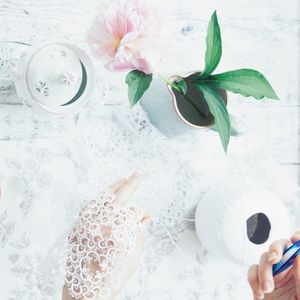 Cropped hands of woman holding patterned white fabric at table