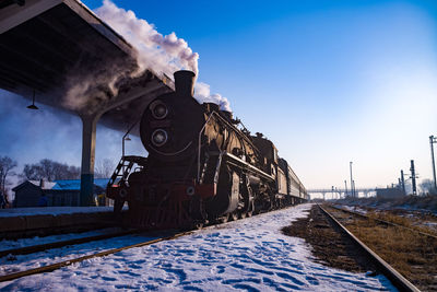 Train on railroad tracks against sky during winter
