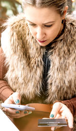 Close-up view of a young woman using her smartphone and credit card to make an online purchase.