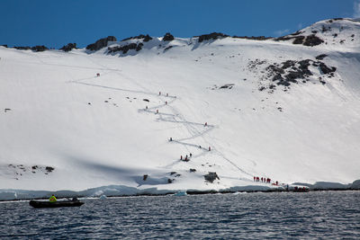 People climbing snowcapped mountain during winter