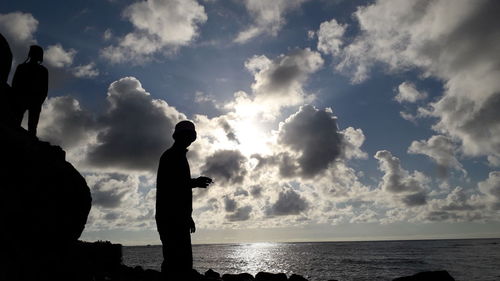 Silhouette man standing by sea against sky