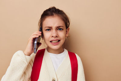 Portrait of young woman using mobile phone against pink background