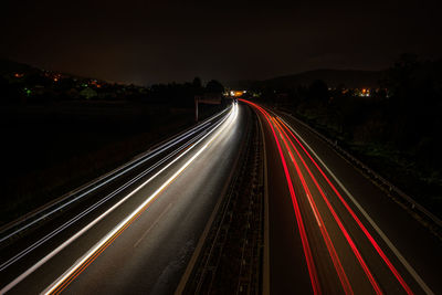 Motorway in night with red and white car light trails glowing