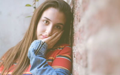 Portrait of young woman looking away against wall