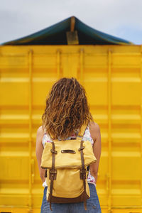 Rear view of woman standing against yellow building