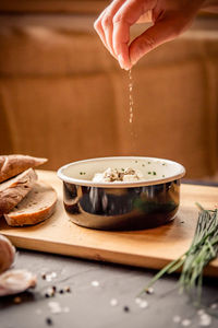 Cropped hand of man pouring food in bowl on table