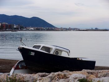 Boat moored on shore by sea against sky