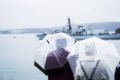 Rear view of people with umbrellas watching ship