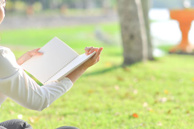 Hand holding book on field