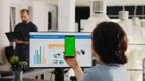 Rear view of woman using mobile phone in office