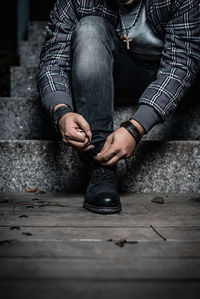 Low section of man tying shoelace