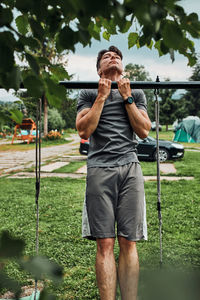 Young man doing pull-ups on pull-up horizontal bar during his calisthenics workout on a camping