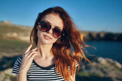 Portrait of young woman wearing sunglasses against sky