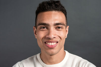 Portrait of smiling young man against black background