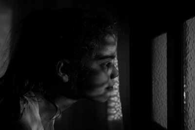 Close-up of girl looking through window